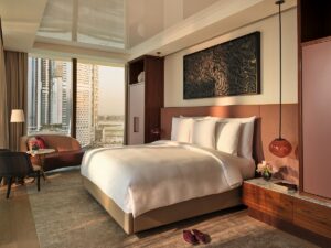 double bed with white linen, and couch in guestroom with views across Dubai at The Lana