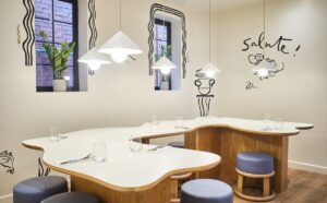 white irregular curved table in private dining area with handpainted wall illustrations