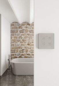 white bathroom with white bath against exposed brick wall with zennio control panel