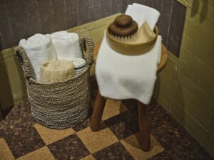 chequerboard design of cork flooring in bathroom with wooden stool, brush and towels