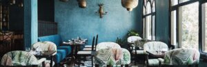 dark blue tadelekt walls and green leaf print fabric on chairs in dining area of Dar Jasmine