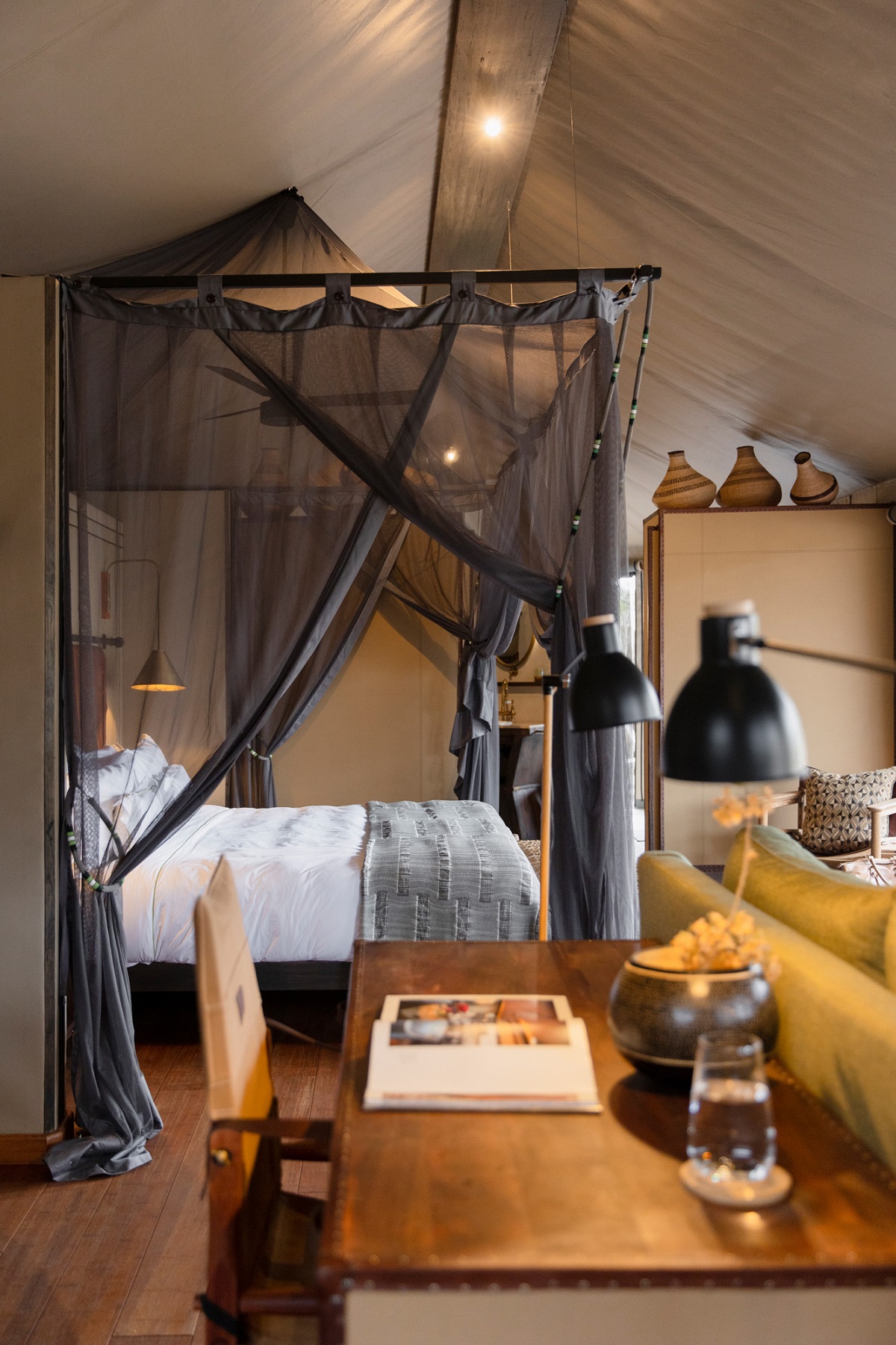 view under tented roof across table to four poster wooden bed