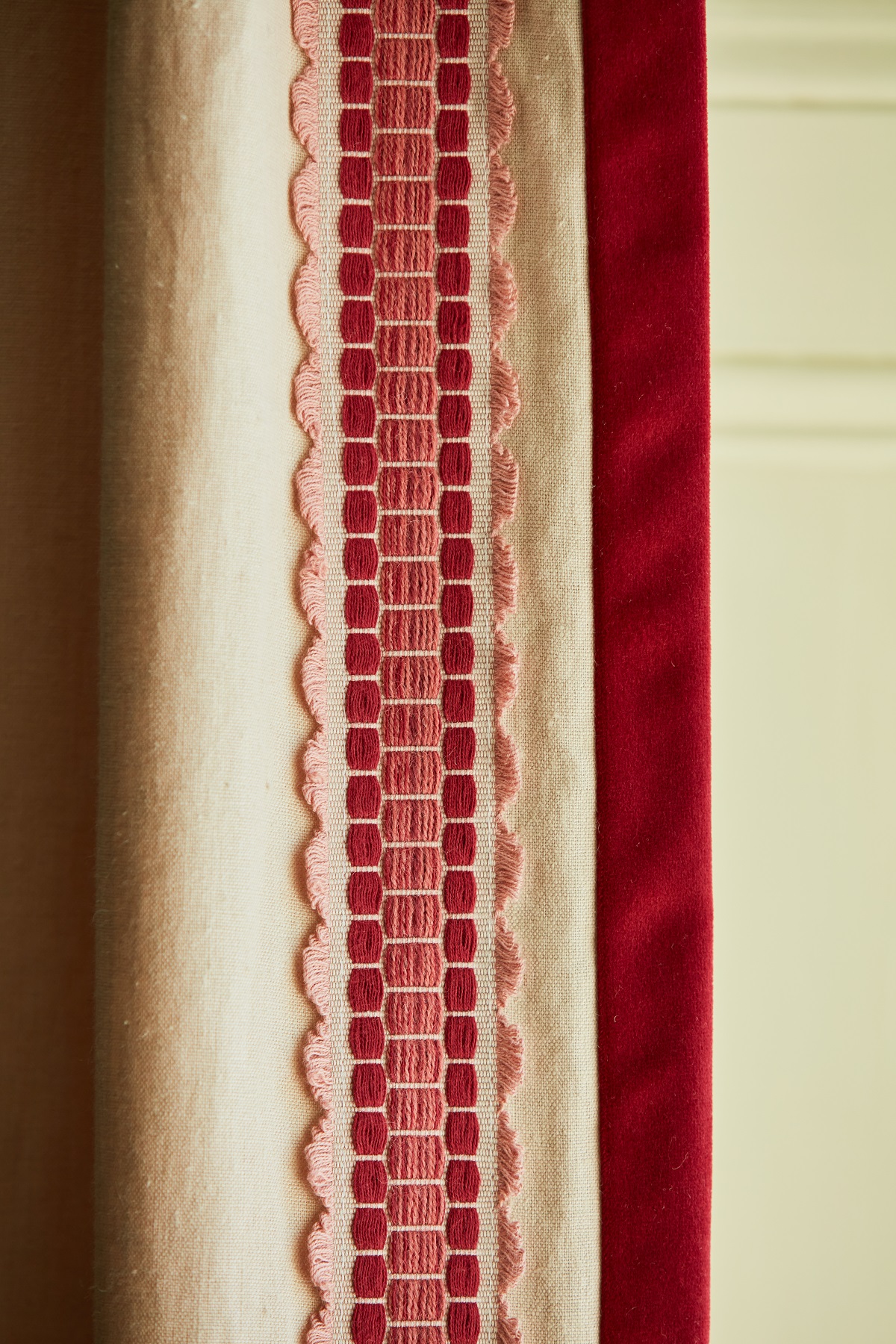cream curtain edged with red decorative trim