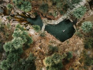 birds eye view of secluded boutique hotel swimming pool between rocks and trees