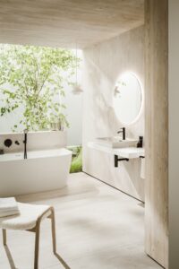 white Laufen bathroom fittings with stone surfaces and green garden space in courtyard behind the bath