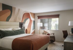 hotel guestroom with painted mural in tones of terracotta behind the bed