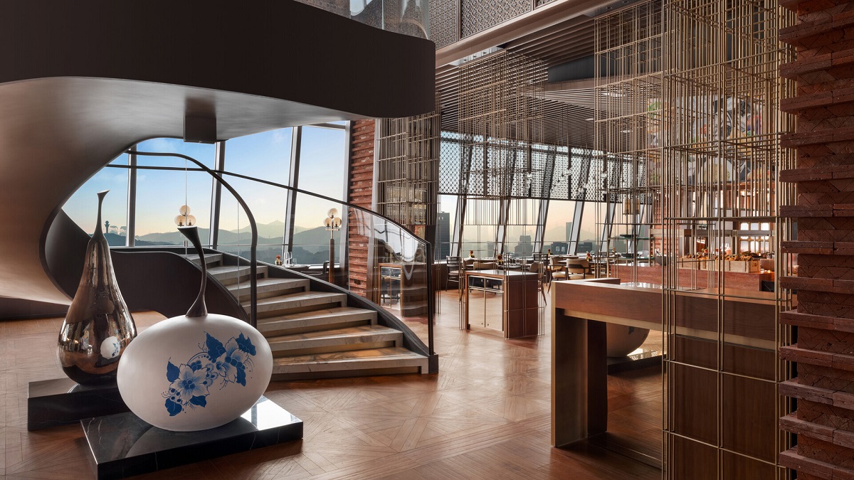 An image of HUIHAI Restaurant featuring a sweeping staircase, parquet flooring, and views across the mountains