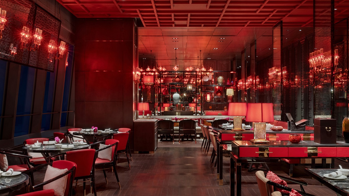 A striking, contemporary restaurant features warm red lighting and mirrored surfaces. 