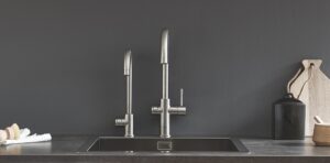 double mixer chrome taps against black wall at kitchen sink