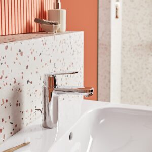 orange bathroom wall with terrazzo splashback and chrome tap
