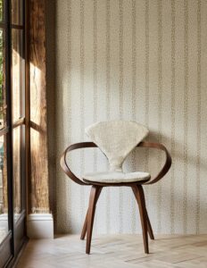 sculptural wooden chair against patterned and striped wallpaper 