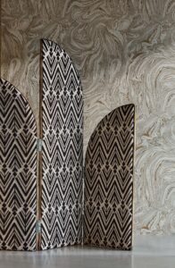 panelled room divider covered in monochromatic print from Harlequin in front of patterned wallpaper 