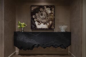 carved bureau with art work above in dark and moody corner