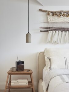 bed with handwoven wallhanging above and ruark radio on sidetable