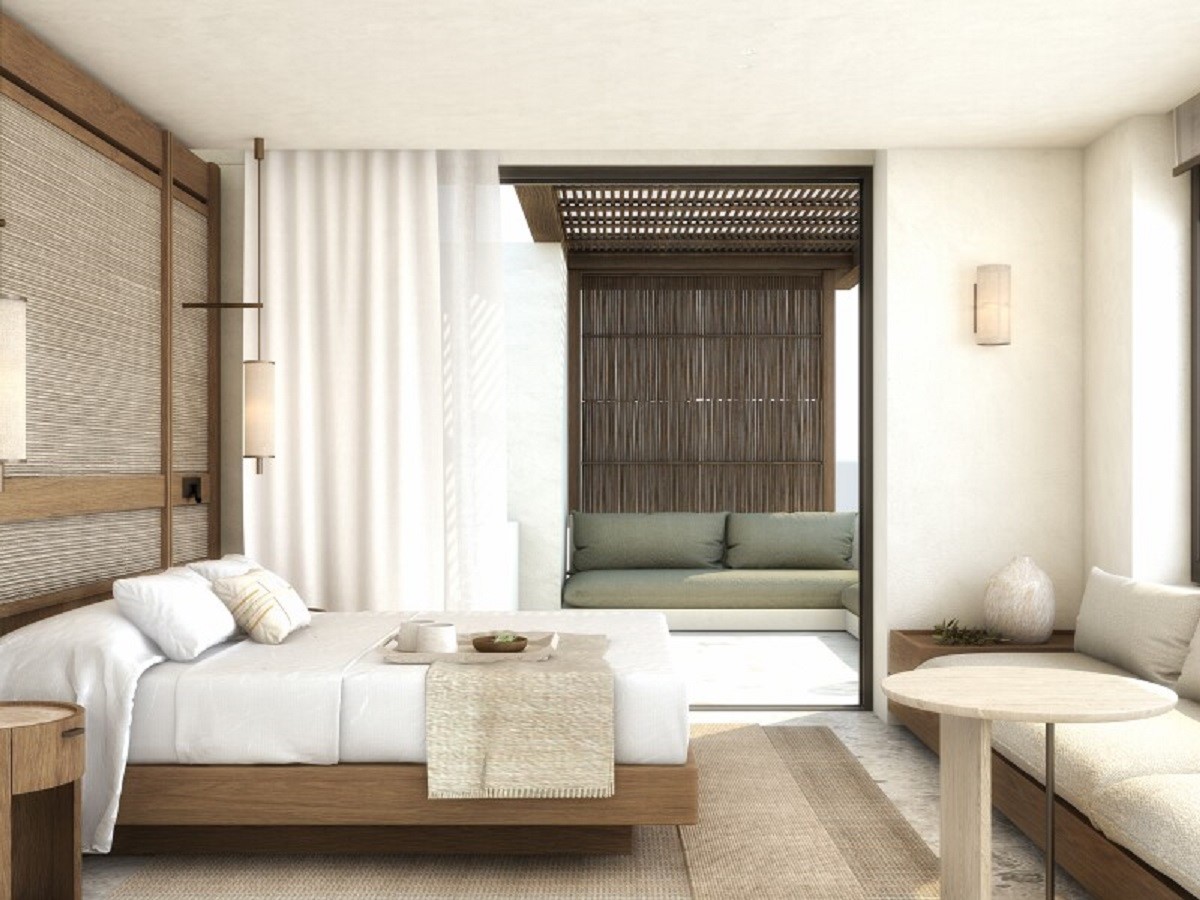 A serene guestroom setting features a floating bed surrounded by natural materials and is bathed in sunlight with a wide doorway leading to an outdoor balcony 