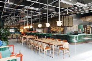 communal dining area and green tiled bar in industrial space of The Social Hub