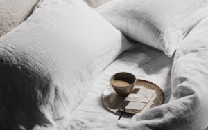 unmade bed with organic naturalmat bed linen and tray with coffee