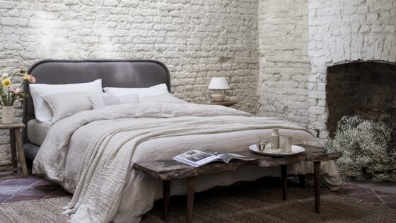 bed with painted brick setting and fireplace , made with organic naturalmat bedlinen