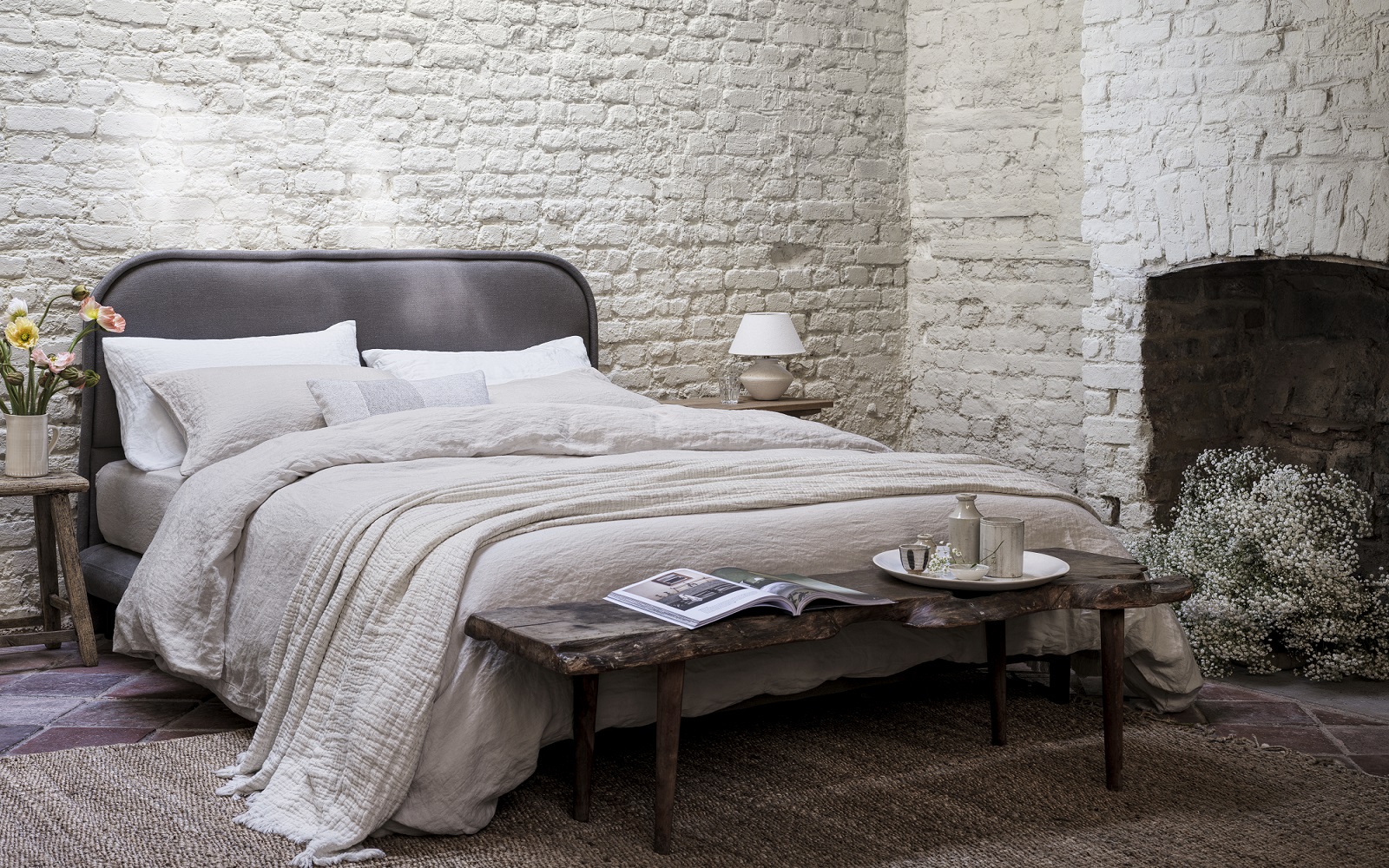bed with painted brick setting and fireplace , made with organic naturalmat bedlinen