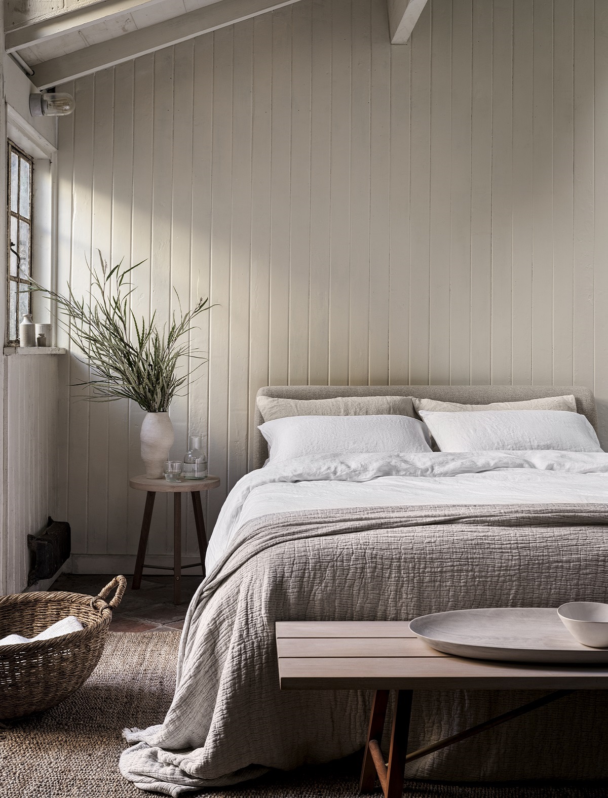 rustic bedroom with painted wooden beam and bed in organic linen sheets