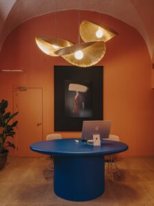 blue table, terracotta walls with art, gold statement light in reception of Palau Fugit
