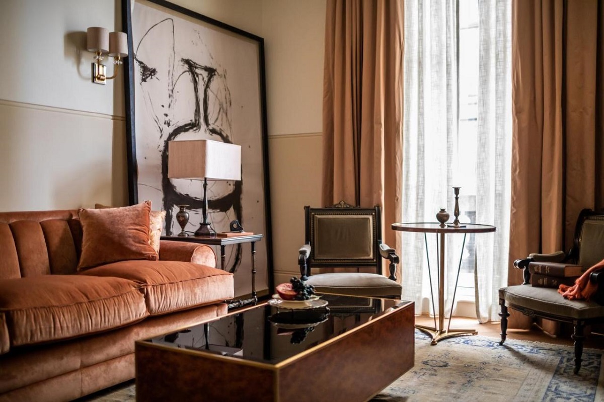 The living room area of a guest suite at the NoMad with a mix of period features and mid-century furniture. Russet tones and a residential feel. 