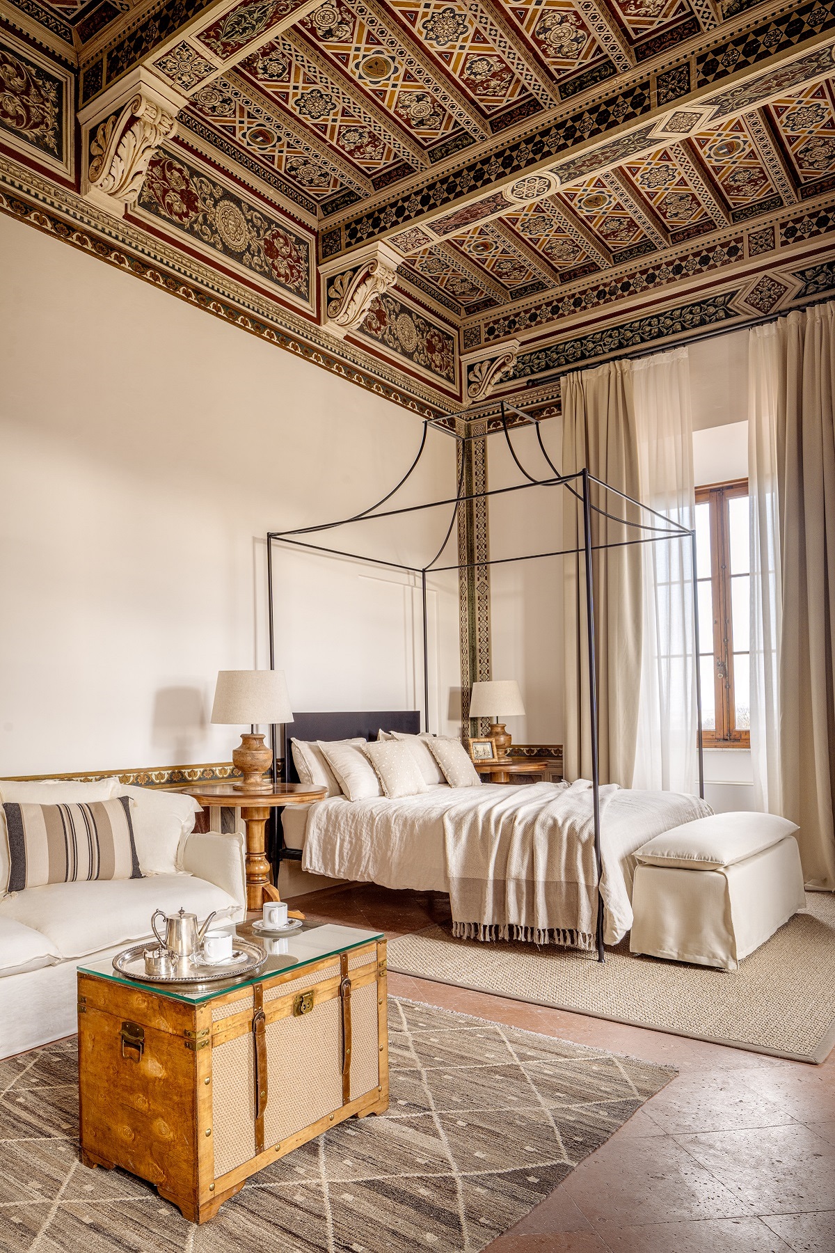 decorative antique ceiling detail and antique four poster bed in tuscan hotel