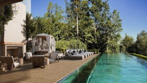 pool side loungers and a swimming pool lined by trees at Rosewood Schloss-Fuschl