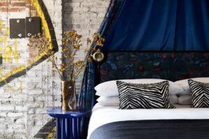 guestroom with graffiti behind the bed with a blue velvet canopy
