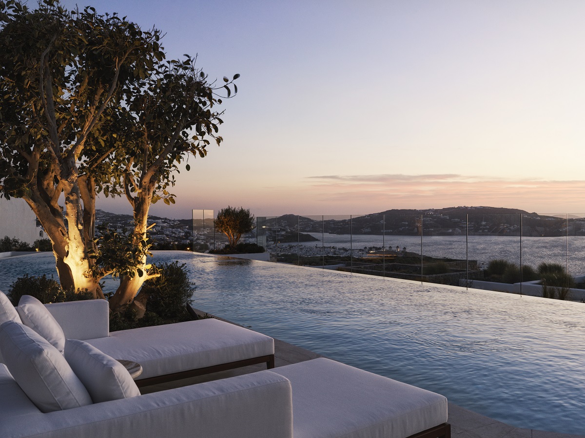 An infinity pool with a view over the townscape and sea in Mykonos at sunset.