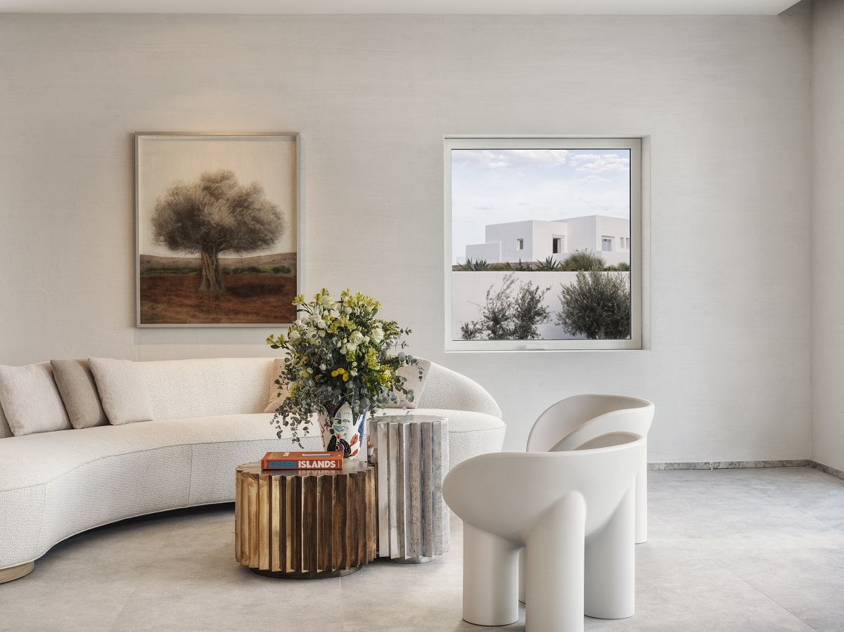 The living room area of a guest suite washed in white and dressed with natural cotton shades in a plush and curvy sofa and playful seat-hugging chairs. 