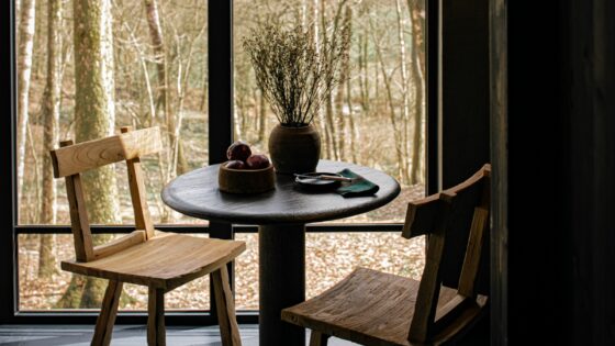 wooden table and chair in front of window looking out to woodland