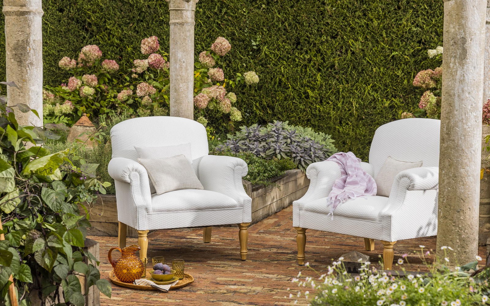 upholstered George Smith chairs in the garden with tea tray