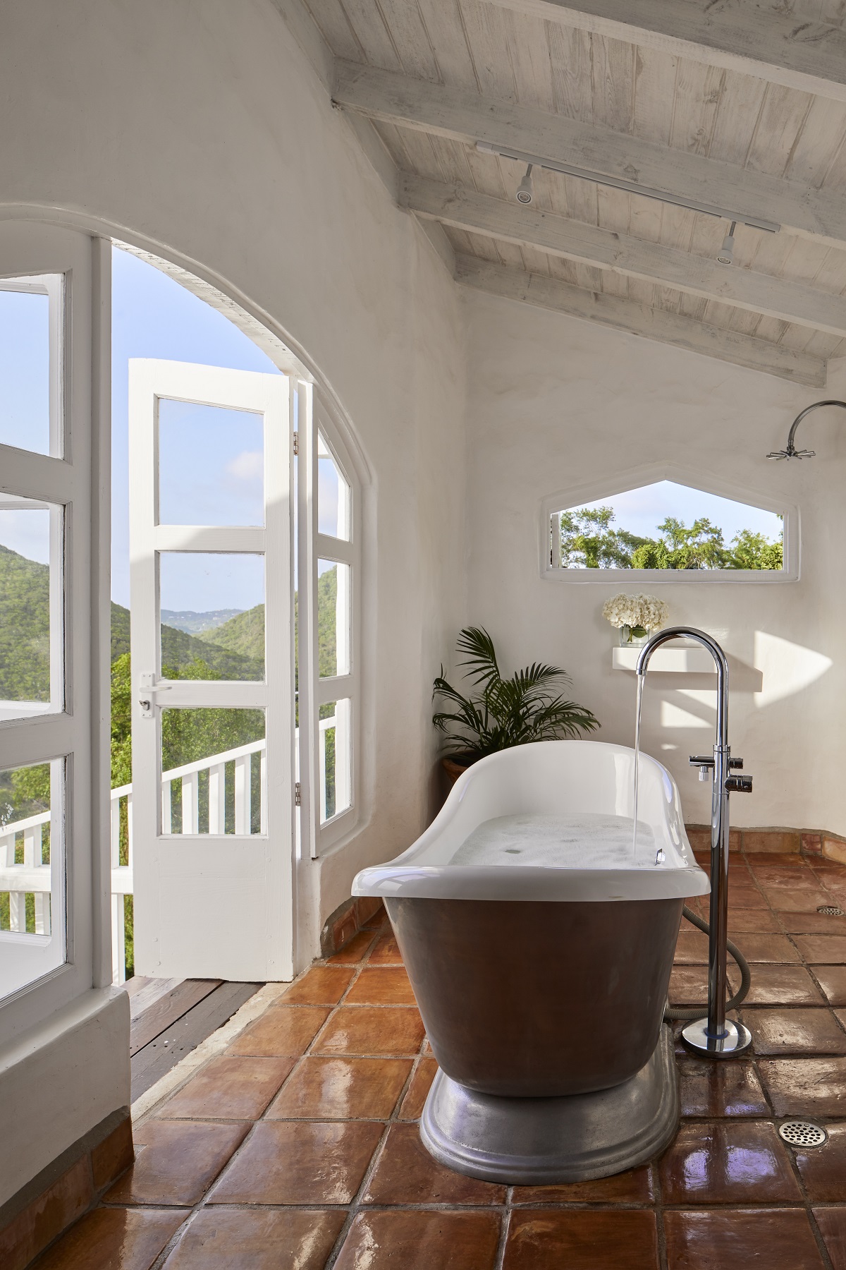 freestanding roll top bath in front of doors and seaview