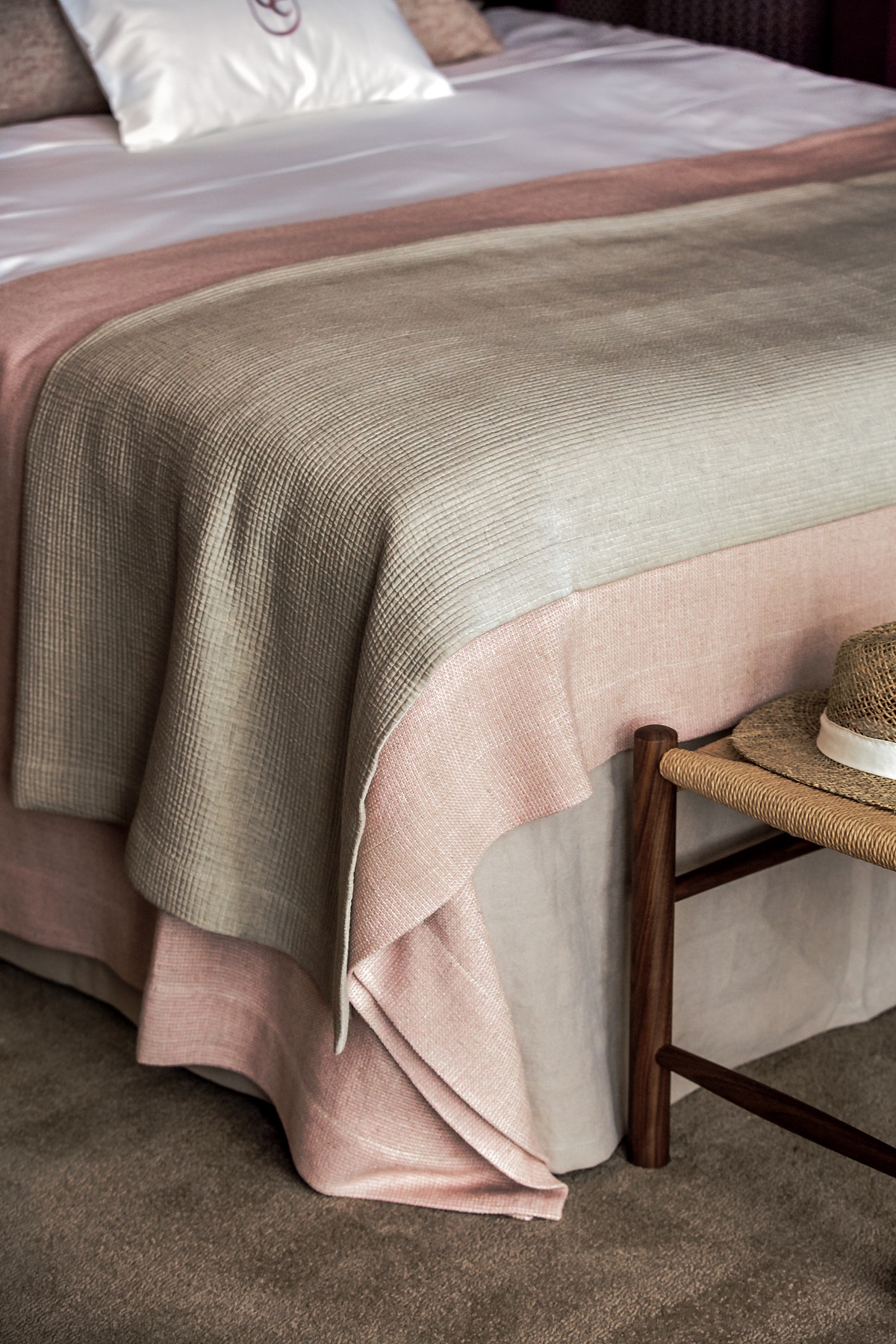 bed detail in guestroom with layered linen in tones and textures