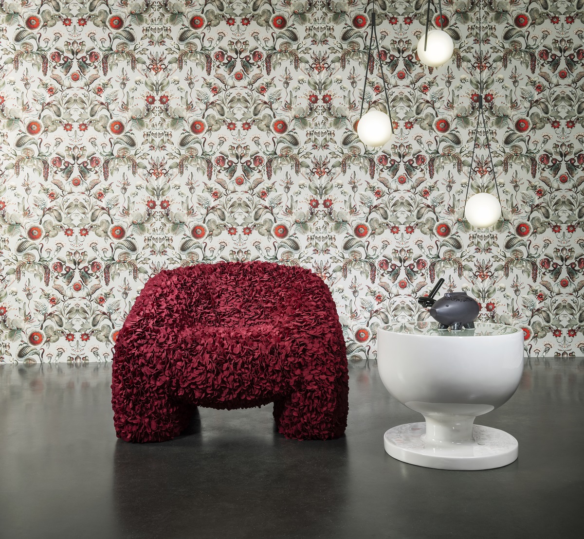 red fluffy chair and white table in front of detailed patterned wallcovering