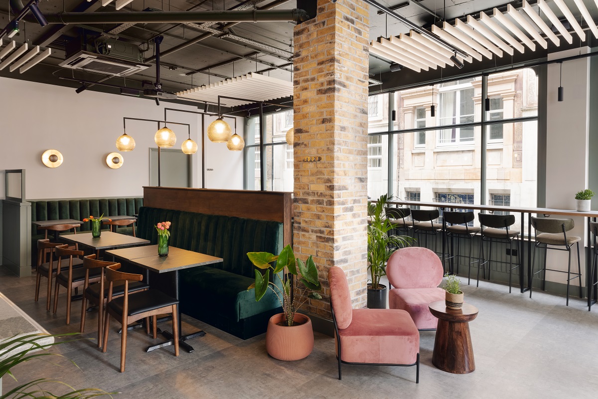 industrial style restaurant with soft pink chair and plants