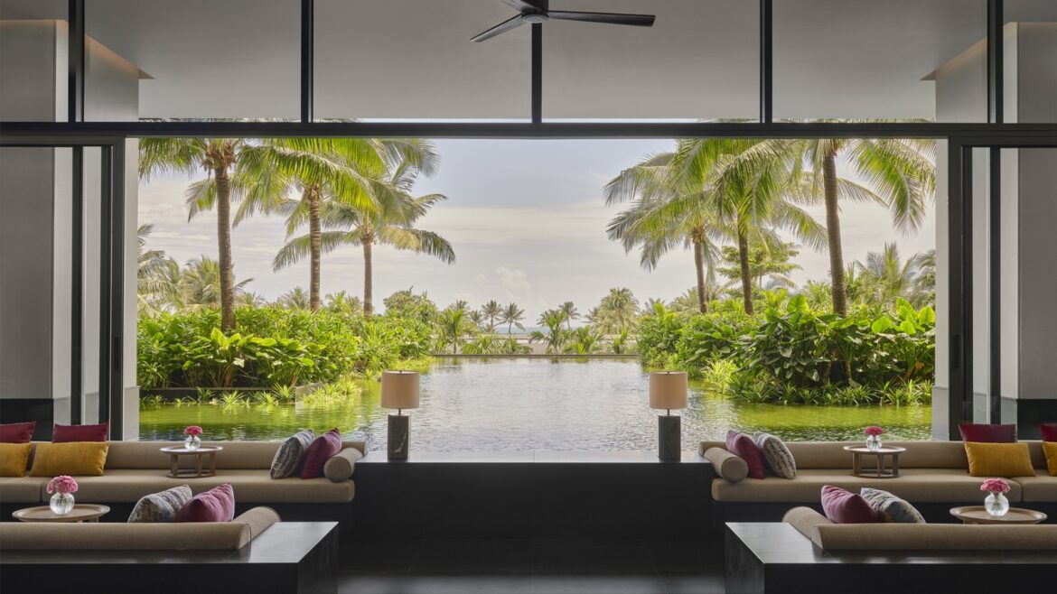 lounge in Regent Phu quoc with windows framing a view of palm trees and pool