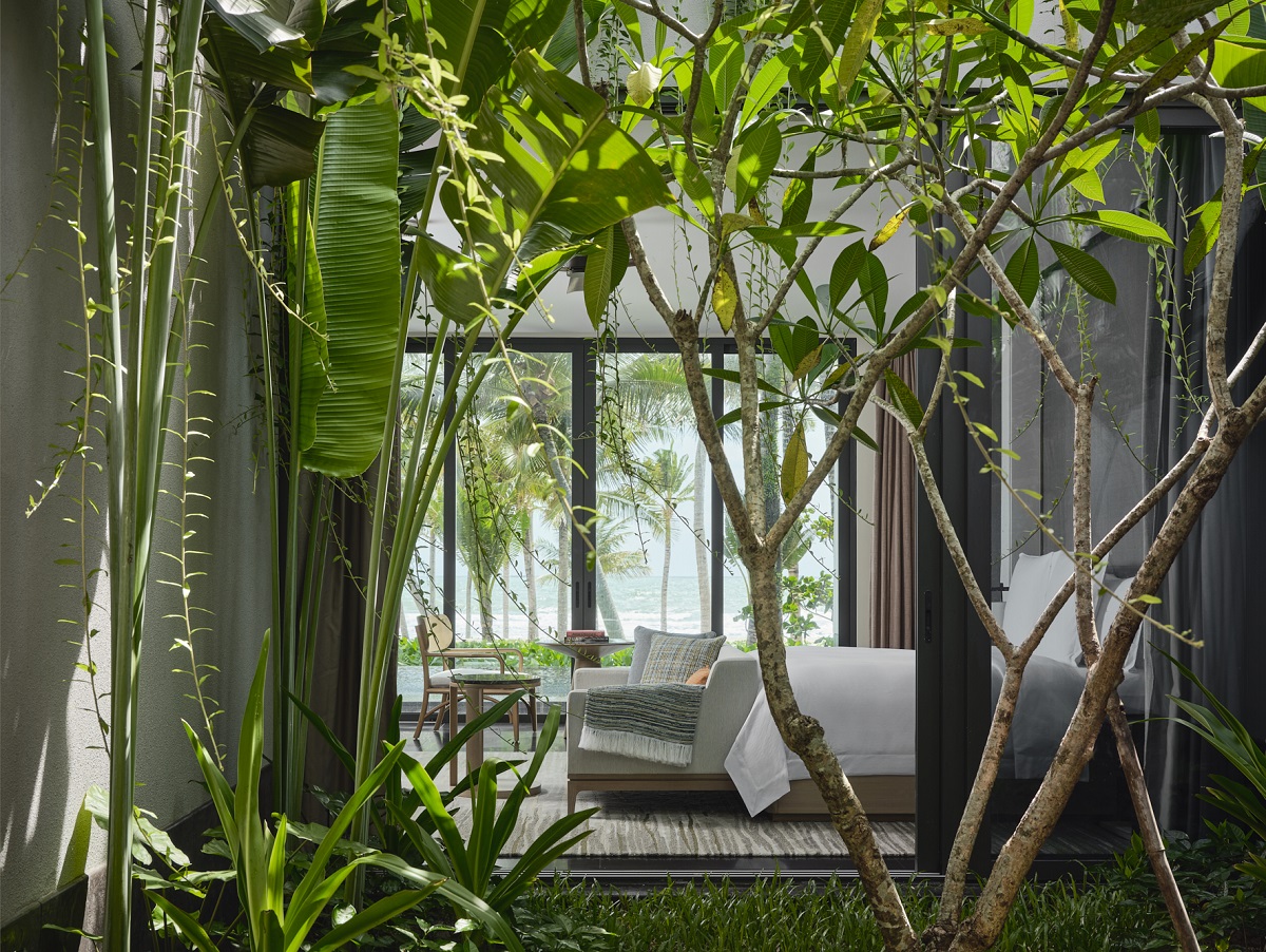 floor to ceiling glass doors surrounded by tropical plants frame ocean views