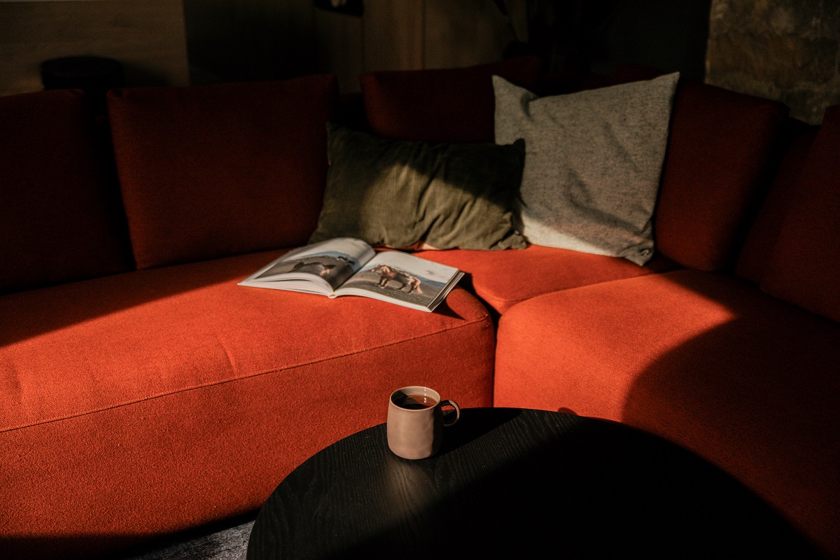 morning light on orange sofa with book and coffee at The Rigg End