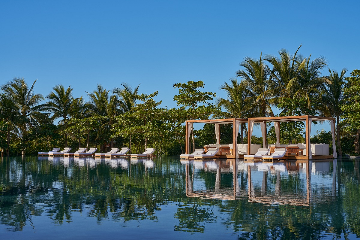 cabanas with white loungers around a pool at The Riviera Maya EDITION Kanai