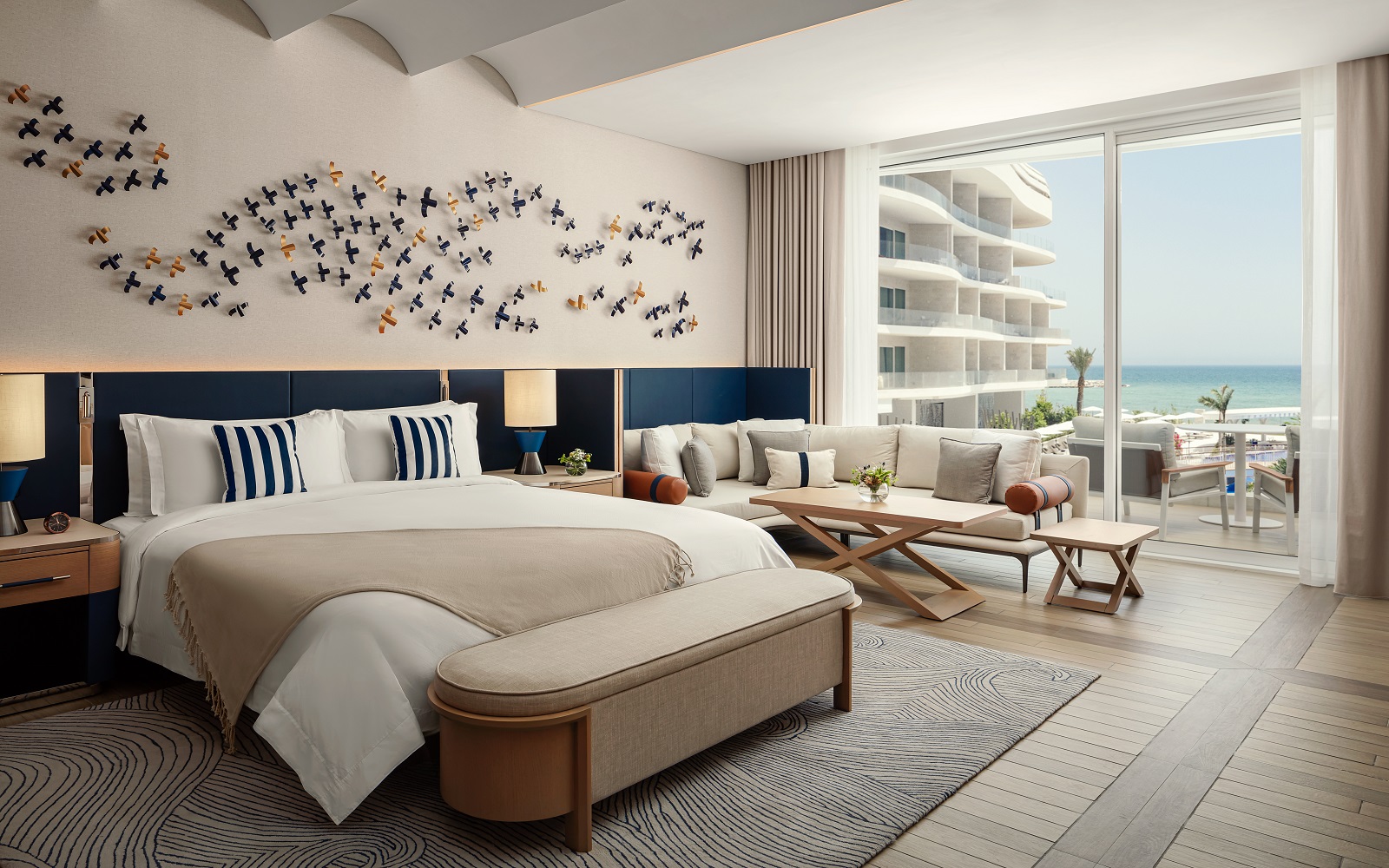 sand coloured throw and blue headboard in guestroom at The St. Regis Al Mouj Muscat Resort