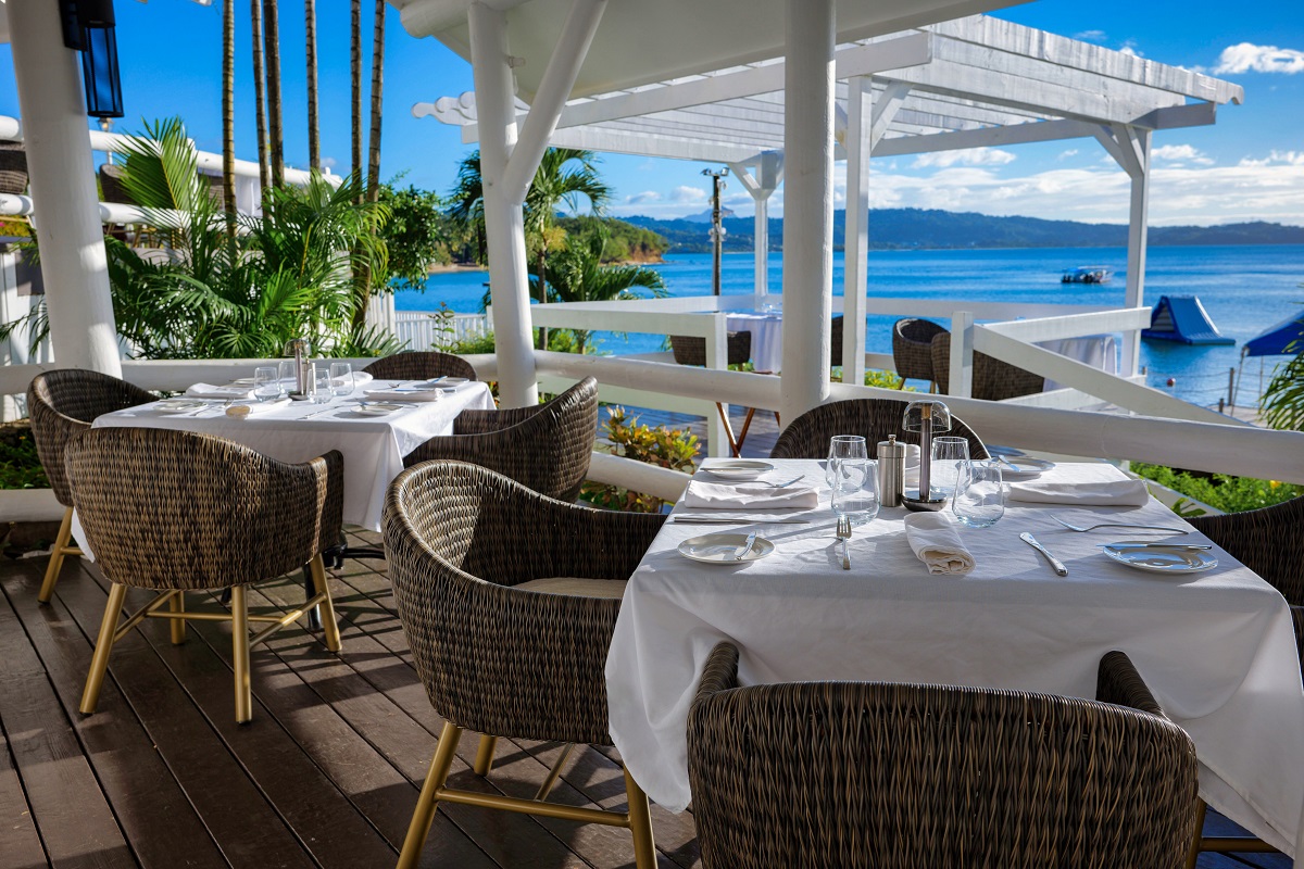 wicker chairs and white linen in restaurant with Caribbean views