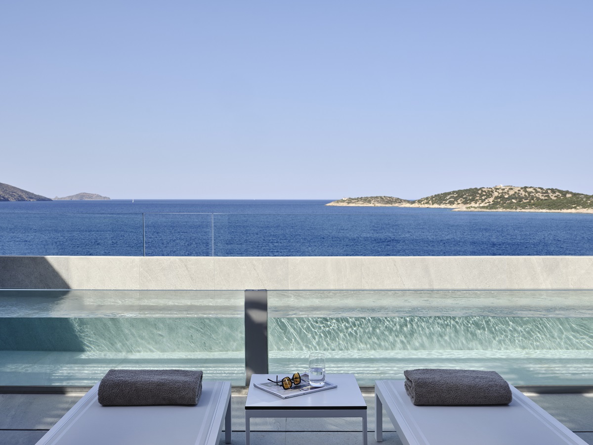 sunloungers on private terrace with view across swimming pool and the sea