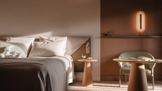 bed with wooden table and chair and wall light in novotel designs by Ligne roset