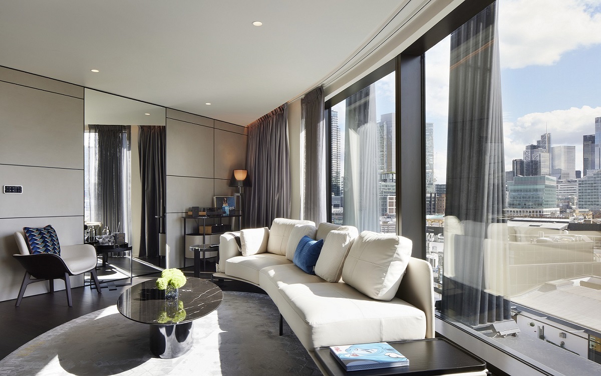 white curved couch along curved glass wall in suite at art’otel London Hoxton