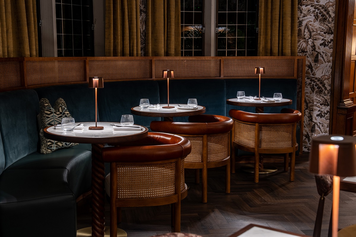 Window bay banquette with round wooden tables and facing chairs