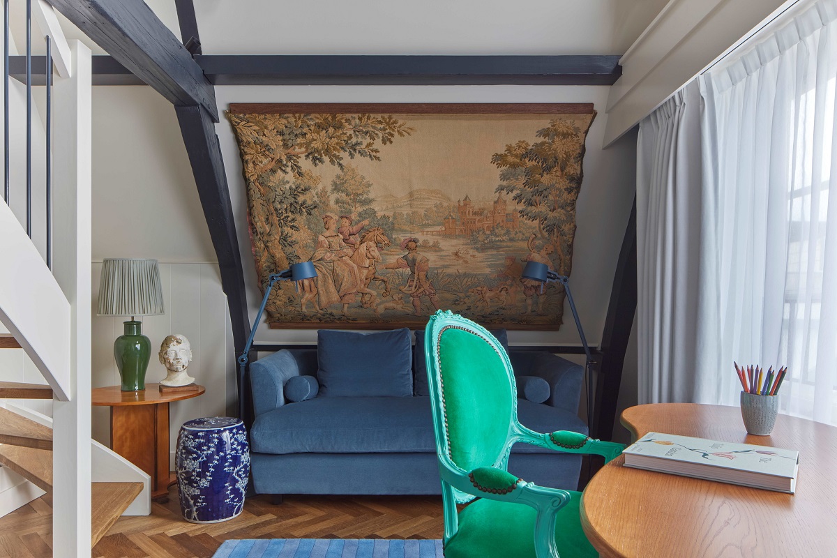 bright green period chair at wooden desk in front of vintage dutch tapestry