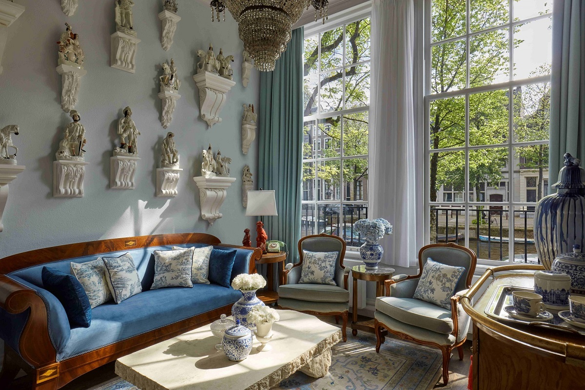 light blue walls with white porcelain displayed as gallery next to windows looking out onto amsterdams canals