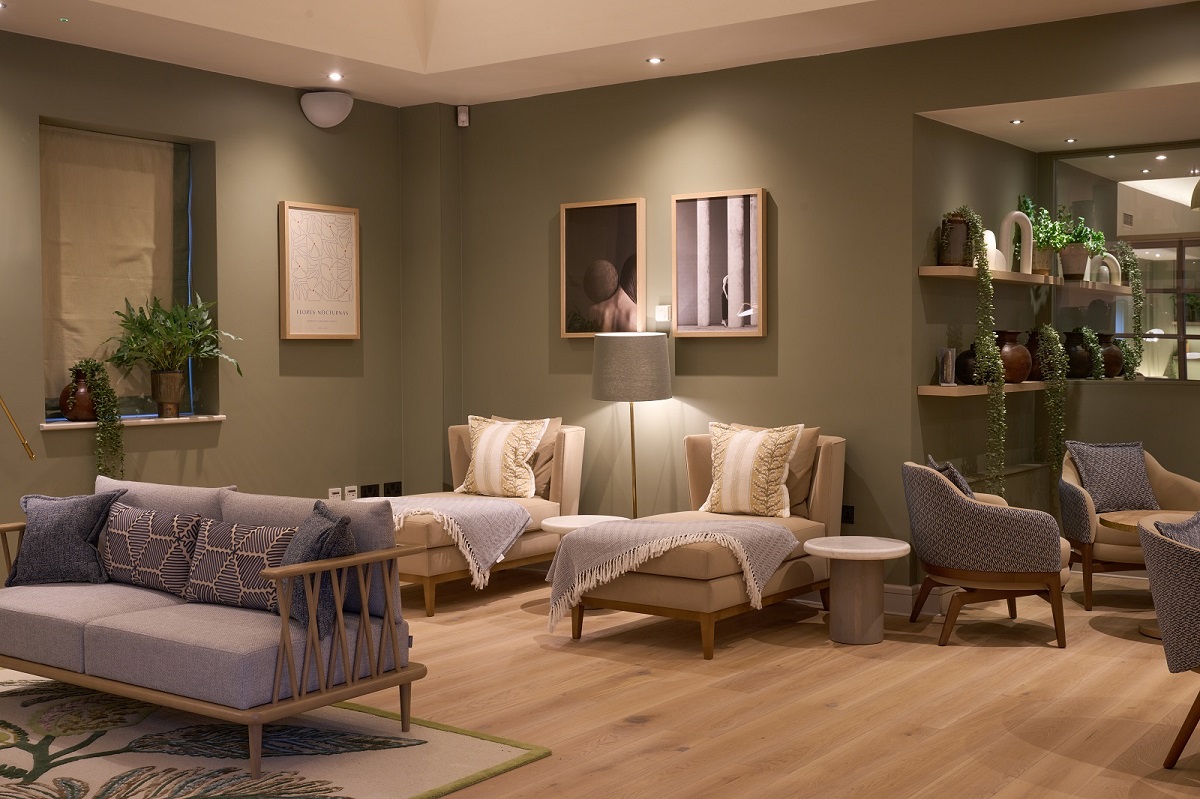 sage green walls and comfortable seating surrounded by plants and wood in the spa